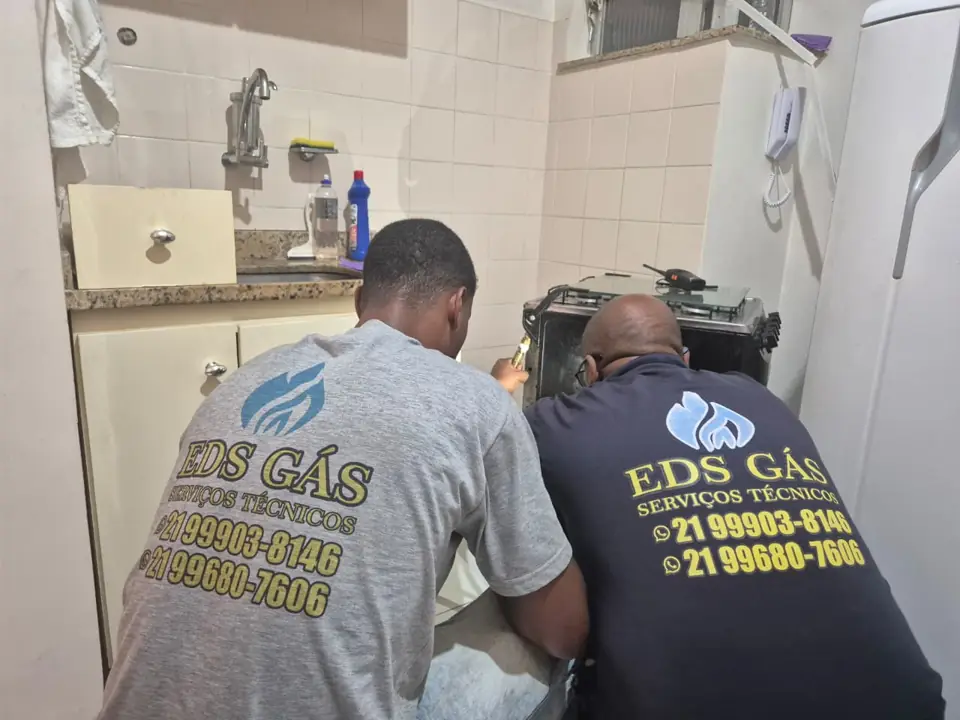 Dois técnicos da EDS GÁS ajustando um fogão em cozinha residencial no Rio de Janeiro